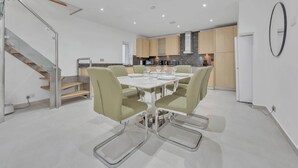 A modern kitchen with a dining area, a staircase, and a large mirror. - Family Town-House Behind Park Lane (London)