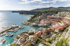 A coastal town with a marina, terraced buildings, and a mountainous backdrop.