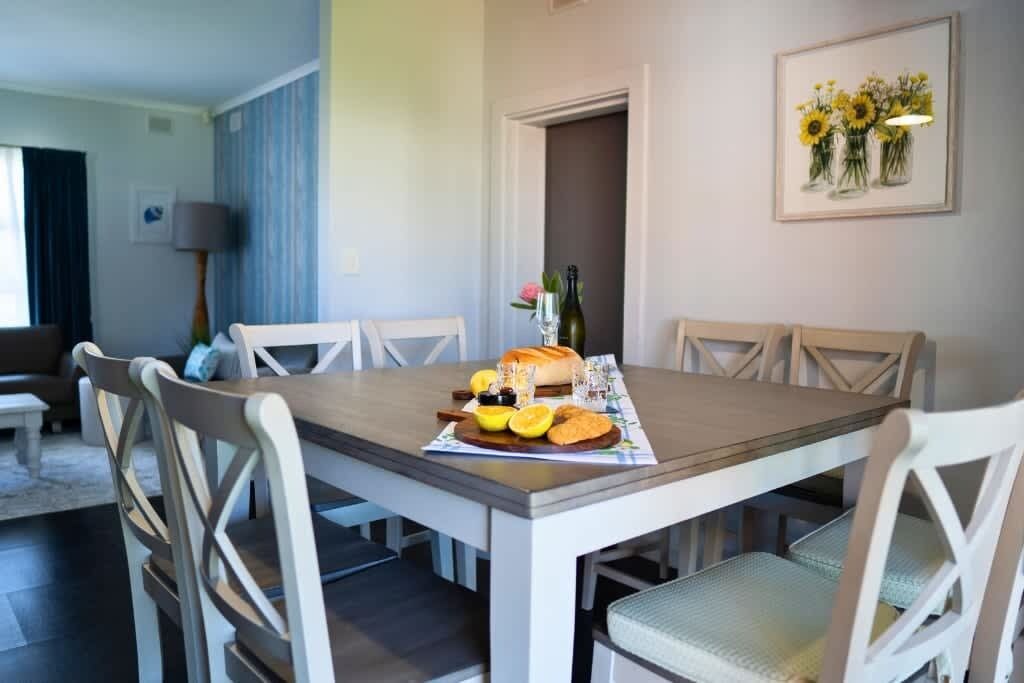 A dining area with a table set for two, a bottle of wine, and a plate with bread and fruit.