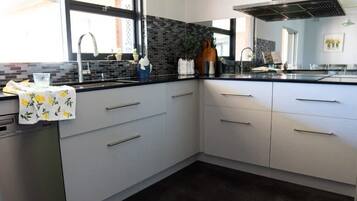 A modern kitchen with a black countertop, white cabinets, a stainless steel sink, and a window providing natural light.