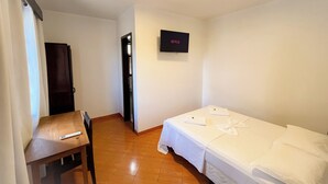 Ein Hotelzimmer mit Bett, Schreibtisch, Stuhl, Fernseher und Tür.