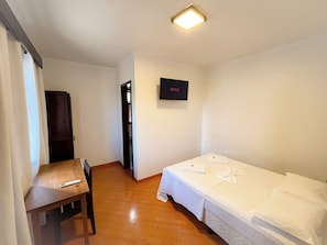 Ein Hotelzimmer mit Bett, Schreibtisch, Stuhl, Fernseher und Tür.