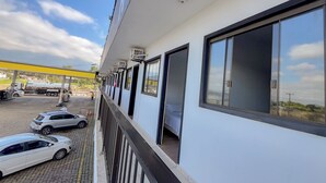A building with a balcony overlooking a parking area with several cars. - Hotel Vandressen & Castro (Garuva)