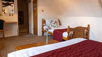 A bedroom with a wooden bed, a red bedspread, a wooden nightstand, and a mirror on the wall.