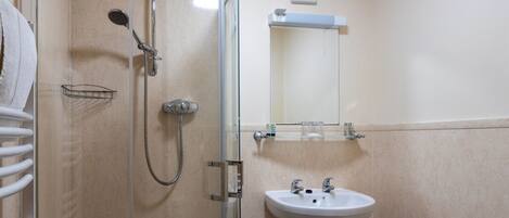 A bathroom with a glass-enclosed shower, a white sink, and a towel rack.