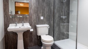 A modern bathroom with a pedestal sink, toilet, and glass-enclosed shower. - The Warehouse (Yeovil)
