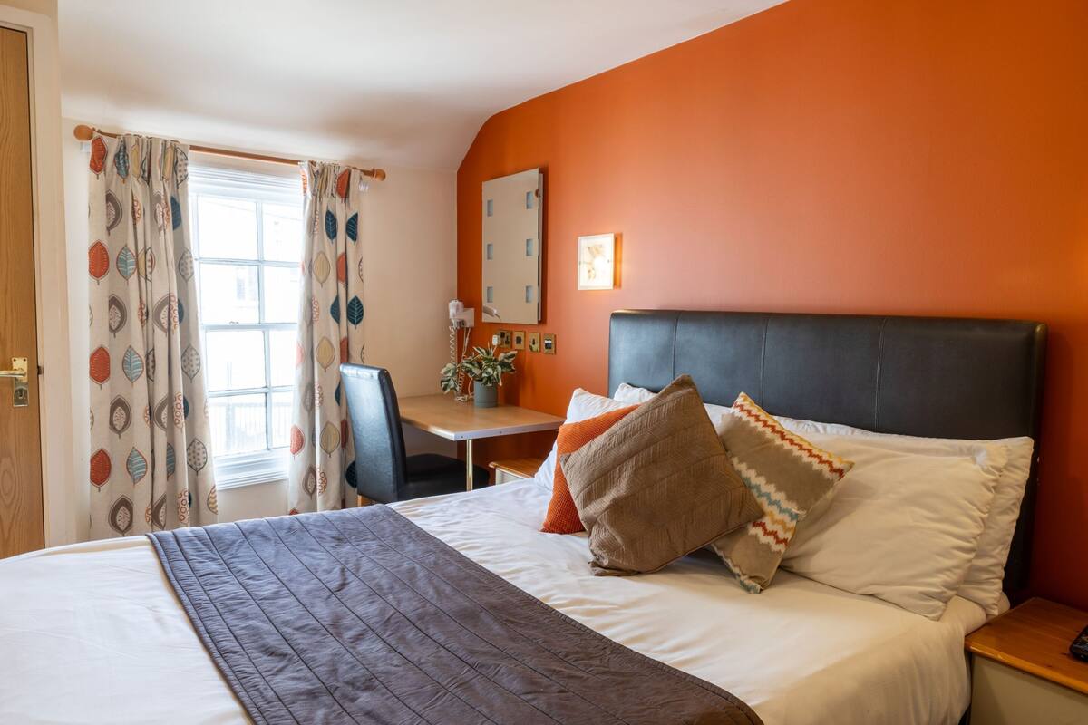 A hotel room with a bed, a desk, and a chair.