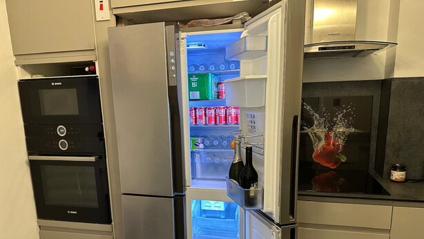 Une cuisine équipée d’un réfrigérateur en acier inoxydable, d’un four Bosch et d’une hotte aspirante Samsung.