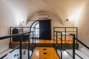 Stairs lead to an upper floor with a yellow-tiled floor and black diamond patterns.