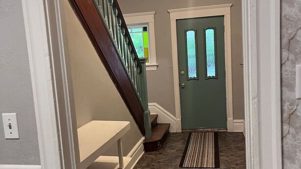 A hallway with a wooden staircase, a green door, and a stone-patterned floor. - Last Minute opening! Dog friendly place! Fenced yard! 3 bed!  (Superior)