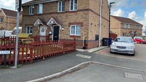 A residential building with a brick facade, a red picket fence, and a 'CLOSE' sign.