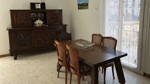 A dining area with a wooden table and chairs, a chandelier, a cabinet with decorative items, and a view through a glass door. - Grande Maison de Village à Estagel (ESTAGEL)