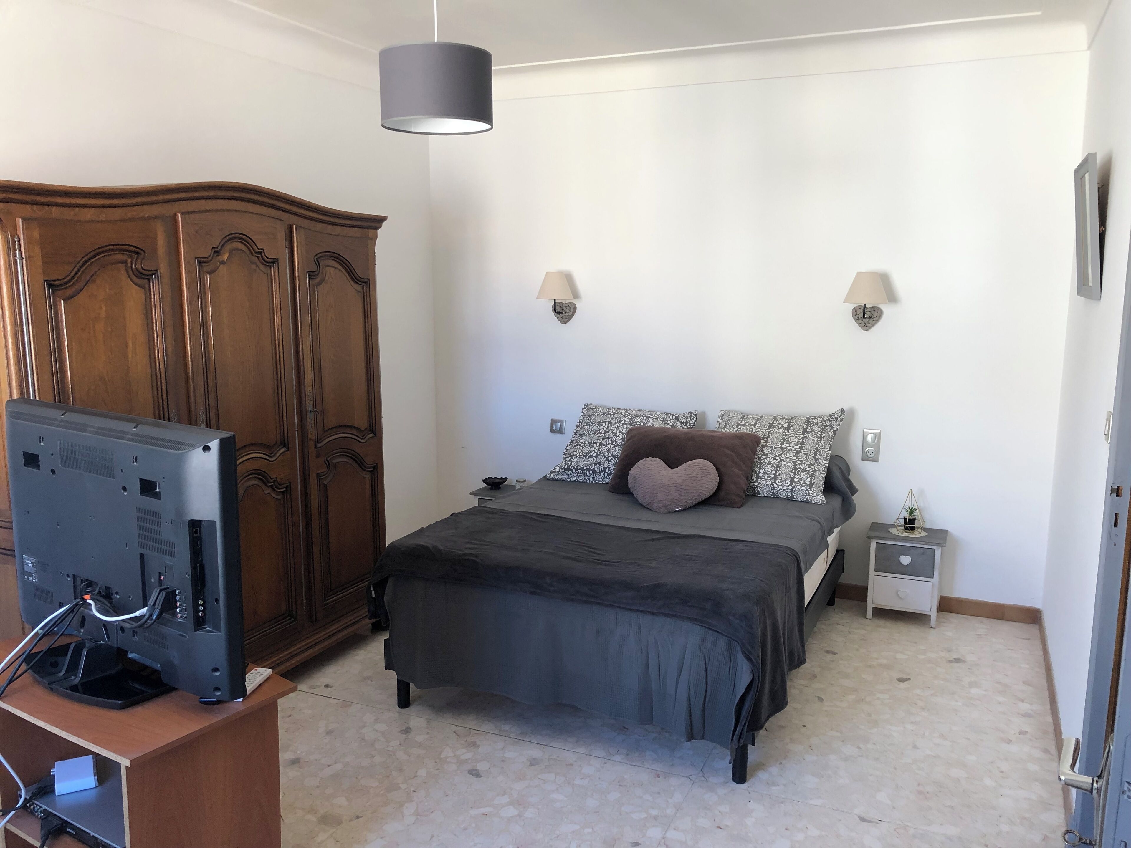 Une chambre à coucher comprenant un lit, une armoire, une table de chevet et un téléviseur.