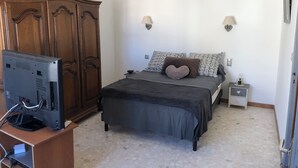 A bedroom with a bed, a wardrobe, a bedside table, and a television. - Grande Maison de Village à Estagel (ESTAGEL)