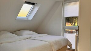 Een slaapkamer met dakraam, een bed en een raam.
