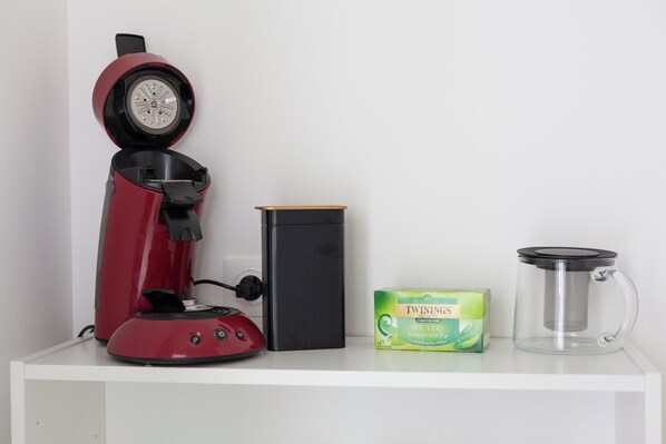 A red coffee maker, a black box, a green box of Twinings tea, and a clear glass teapot on a white shelf. - Villa Julian Piscine Chauffée (Sanary-sur-Mer)