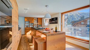 A modern kitchen with wooden cabinetry, a central island, and a large window offering a mountain view.