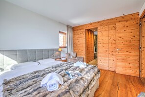 A modern hotel room with two beds, a large window, wooden walls, and a cozy atmosphere. - Boutique Chalet Moritz for 12 With Sauna (Samedan)