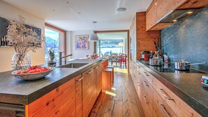 A modern kitchen with wooden cabinets, a large island, and a view to the dining area.