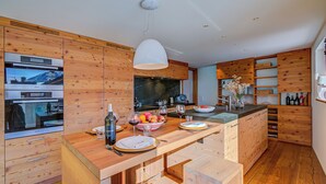 A modern kitchen with wooden cabinetry, a central island, and built-in appliances.