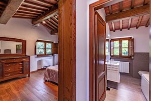 A bedroom with wooden flooring, a bed, a dresser, and a window. - Villa Vittoriano - Surrounded By Nature (Camaiore)
