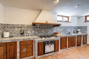 Een keuken met een betegelde spatwand, houten kastjes, een fornuis en een gootsteen.