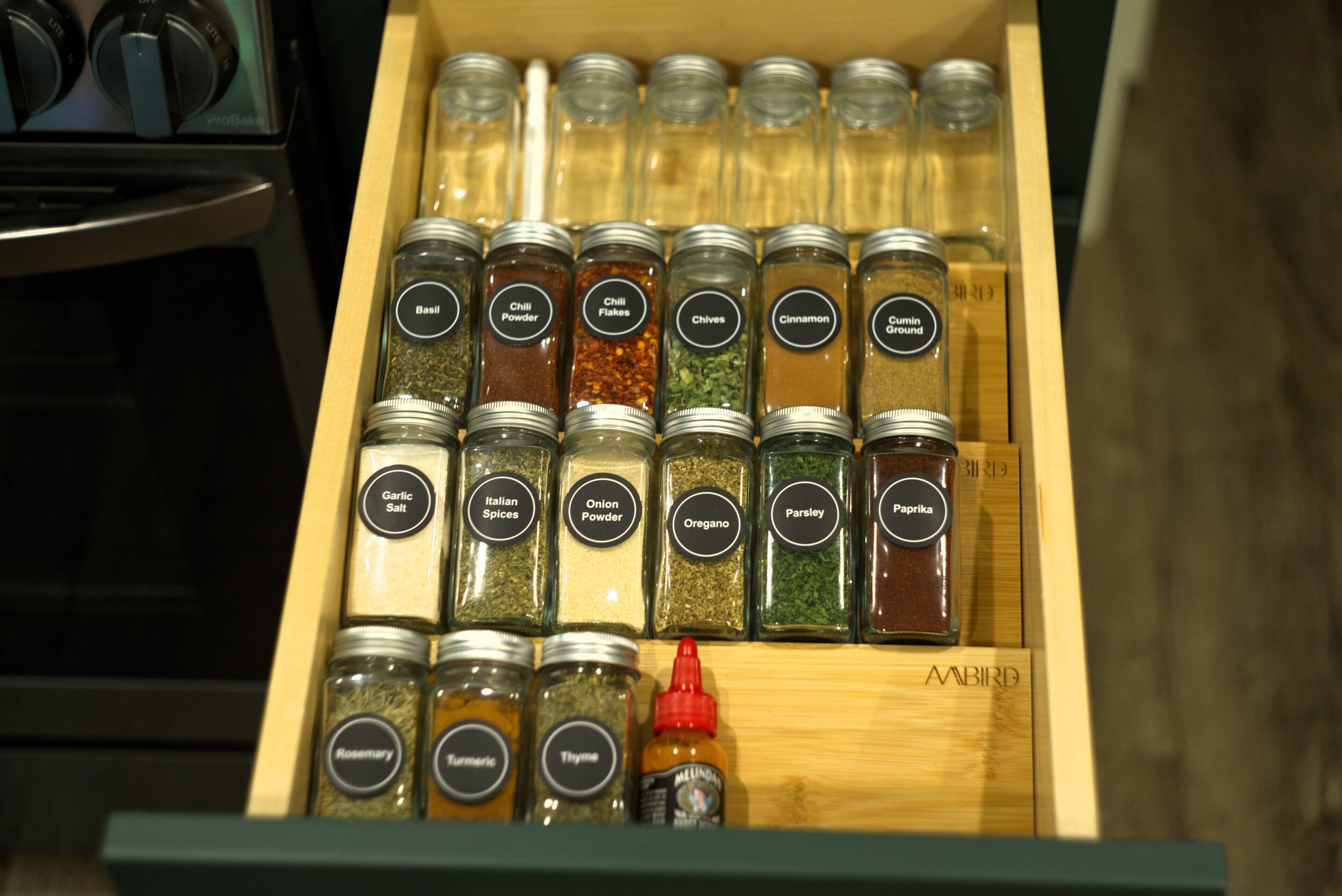Un tiroir contenant diverses épices et herbes, notamment du basilic, du piment en poudre et de la cannelle.