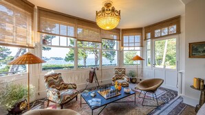 A room with large windows, a chandelier, and a chessboard on a table. - Villa Haute Guais  (Dinard)