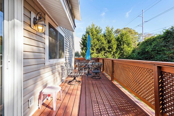 A wooden deck with a table and chairs, a blue umbrella, and a wooden fence.