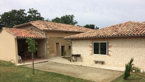 A two-story house with a tiled roof, a stone exterior, and a small front yard. - Gîte des 3 Puits (Caumont)