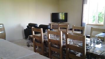 Una zona de dinar amb una taula preparada per a sis, envoltada de caires de fusta. Un televisor de pantalla plana està penjat a la paret sobre la taula.