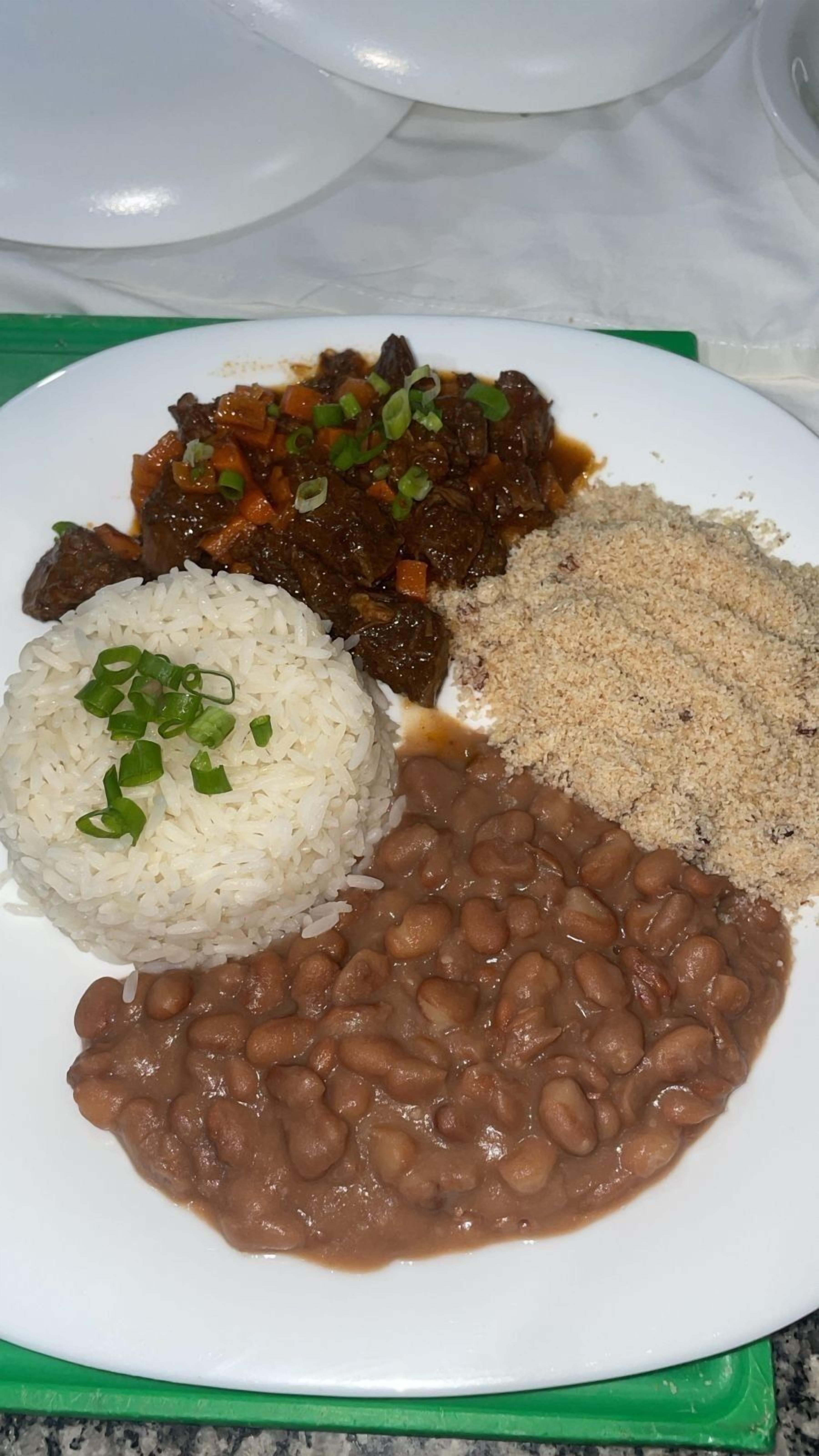 A plate with white rice, brown beans, and a meat dish.