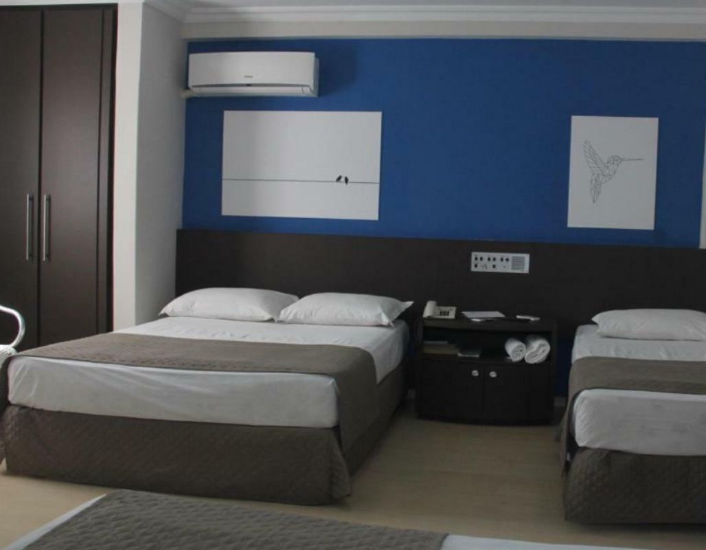 Een slaapkamer met twee bedden, een garderobe, een nachtkastje en een wandairconditioner.