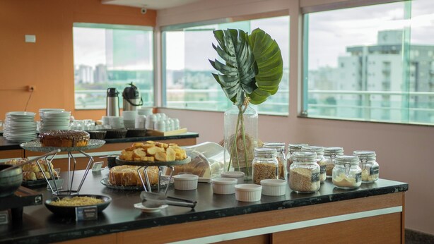 Un buffet proposant une variété de plats, un coin café et une vue sur la ville grâce à de grandes fenêtres.