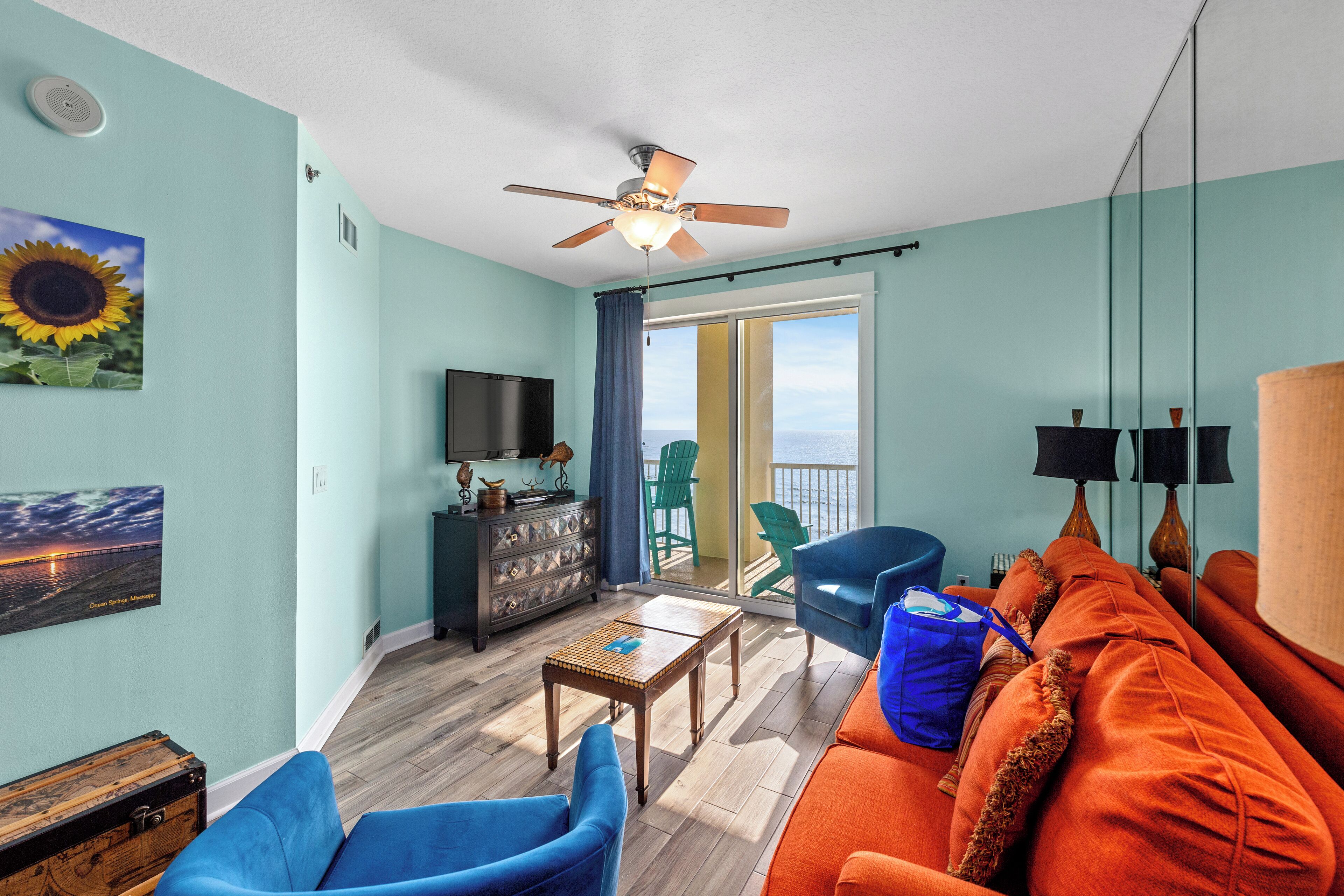 A living room with a sofa, chairs, a television, and a balcony with a view.