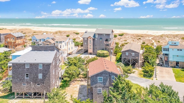 A coastal residential area with various houses, some under construction, and a beach in the background.