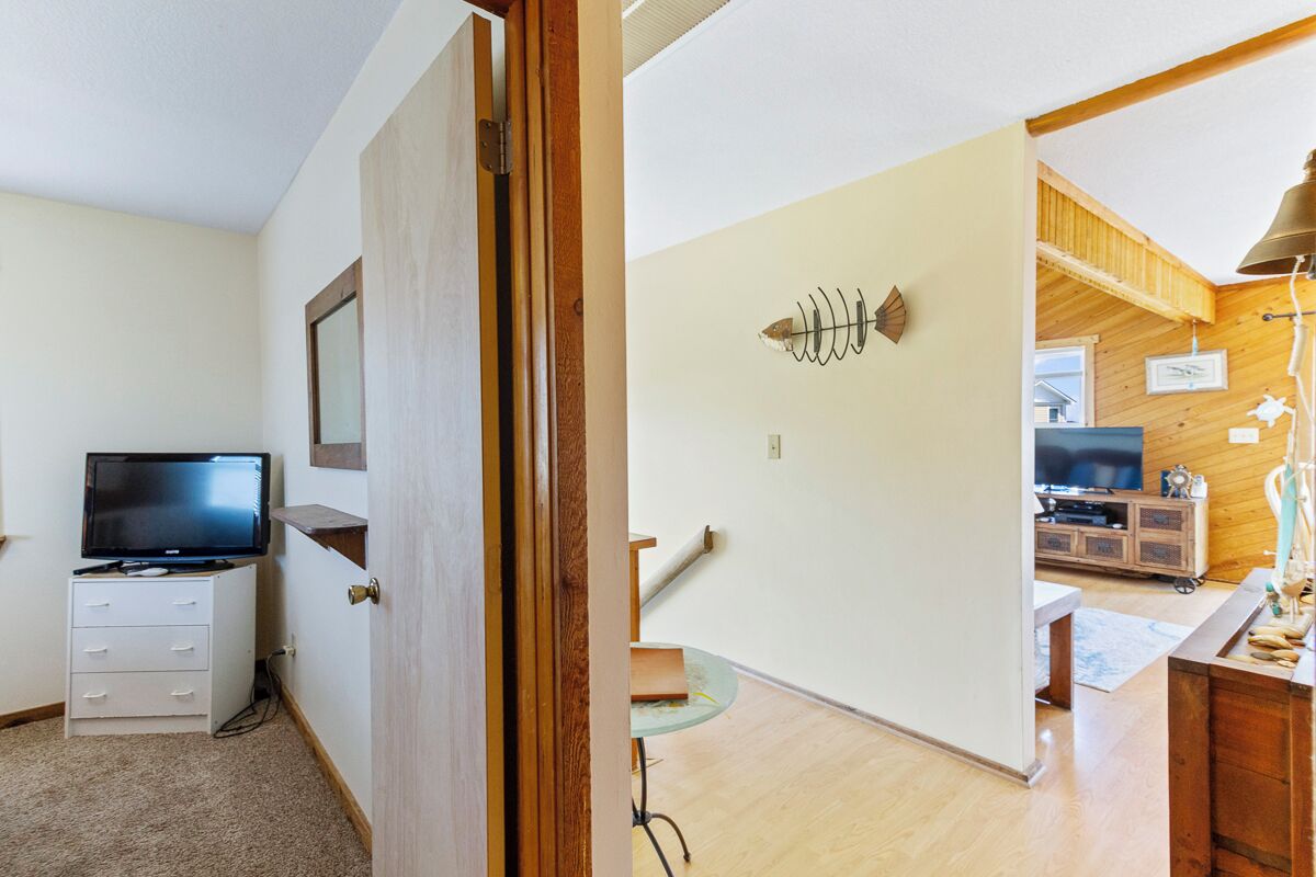 A room with a television on a stand, a desk with a lamp, and a wooden cabinet.