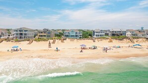 A beachfront property with multiple houses, a sandy beach, and ocean waves. - Beautiful oceanfront home in Duck with gorgeous views! (Duck)