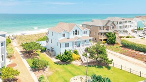 A coastal residential area with houses, a beach, and a clear sky. - Beautiful oceanfront home in Duck with gorgeous views! (Duck)