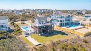 A large, multi-story house with a pool, surrounded by a wooden deck and a fenced yard. - Well-appointed Corolla beach house, just steps from the beach! (Corolla)