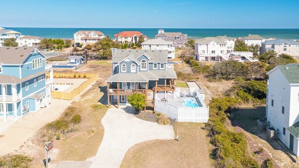 A coastal residential area with houses, a swimming pool, and a clear view of the ocean. - Well-appointed Corolla beach house, just steps from the beach! (Corolla)