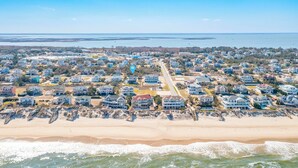 A coastal residential area with houses along the beach, a clear view of the ocean, and a distant body of water. - Well-appointed Corolla beach house, just steps from the beach! (Corolla)