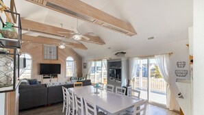 A spacious living area with a dining table, sofa, and TV. - Well-appointed Corolla beach house, just steps from the beach! (Corolla)