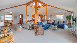 A spacious living area with a high ceiling and exposed wooden beams, furnished with sofas, chairs, and a coffee table.