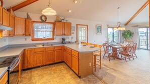 A spacious kitchen with wooden cabinets, a large island, and a dining area with a table and chairs.