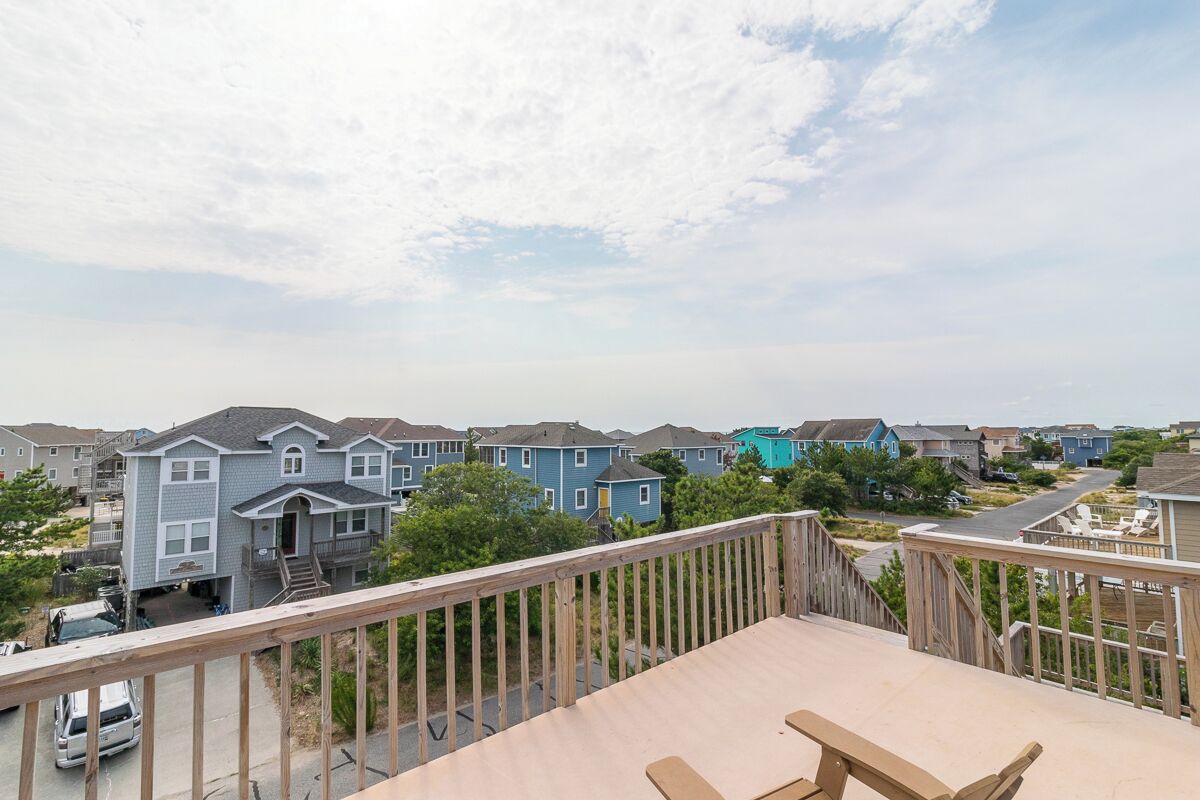 A residential neighborhood with houses, a wooden deck, and a car parked on the street.