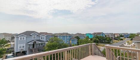 A residential neighborhood with houses, a wooden deck, and a car parked on the street.