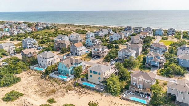 A coastal residential area with houses, a beach, and a swimming pool.