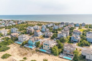 A coastal residential area with houses, a beach, and a swimming pool.