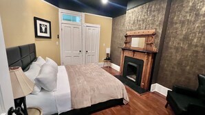 Un dormitorio con cama, mesita de noche, chimenea y puerta.
